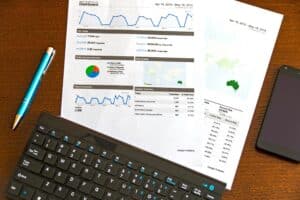 A keyboard and papers on a table showing Google Analytics website traffic data.